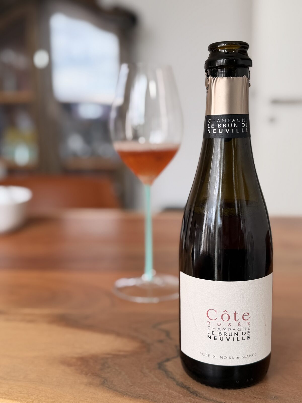 Le Brun de Neuville C&ocirc;te Ros&eacute;e Champagne half-bottle beside a Riedel Fatto a Mano Champagne glass with a turquoise Murano-style stem, salmon-pink rosé in the bowl