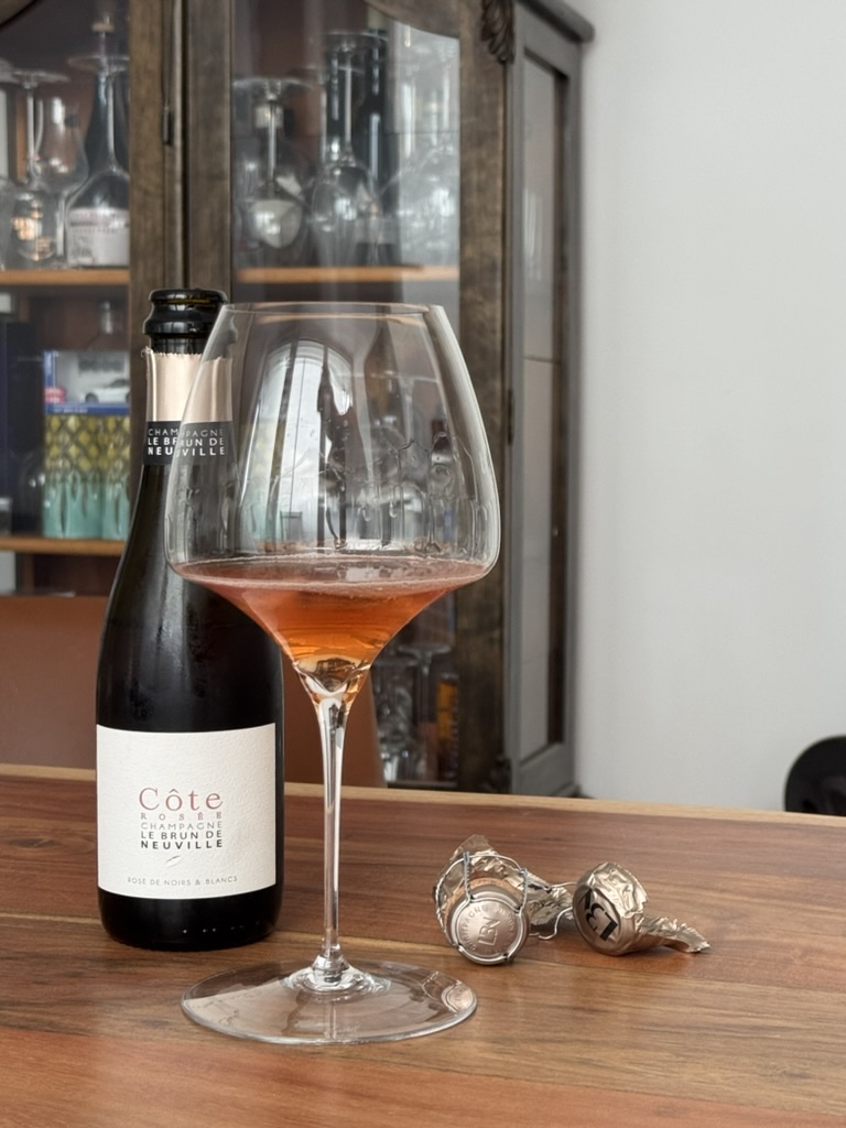 Le Brun de Neuville C&ocirc;te Ros&eacute; Champagne in a Riedel Pinot Noir / Burgundy glass, crumpled muselet cage beside the bottle