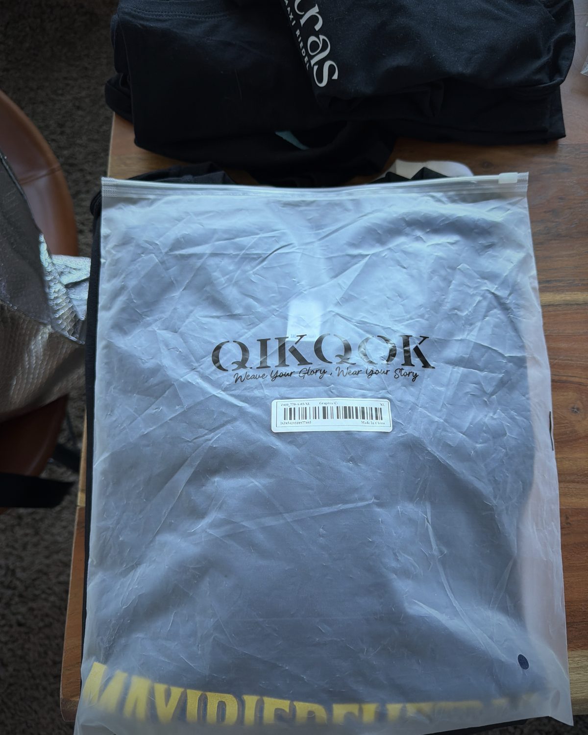 Graphite T-shirt in packaging with a large gold blockbuster wordmark